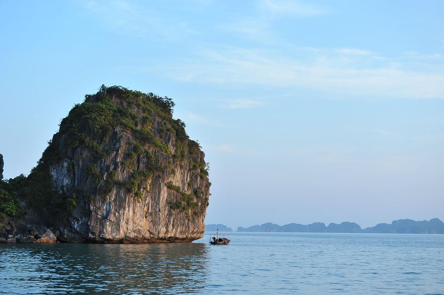 Traditional junk boat cruising through Ha Long Bay at sunset