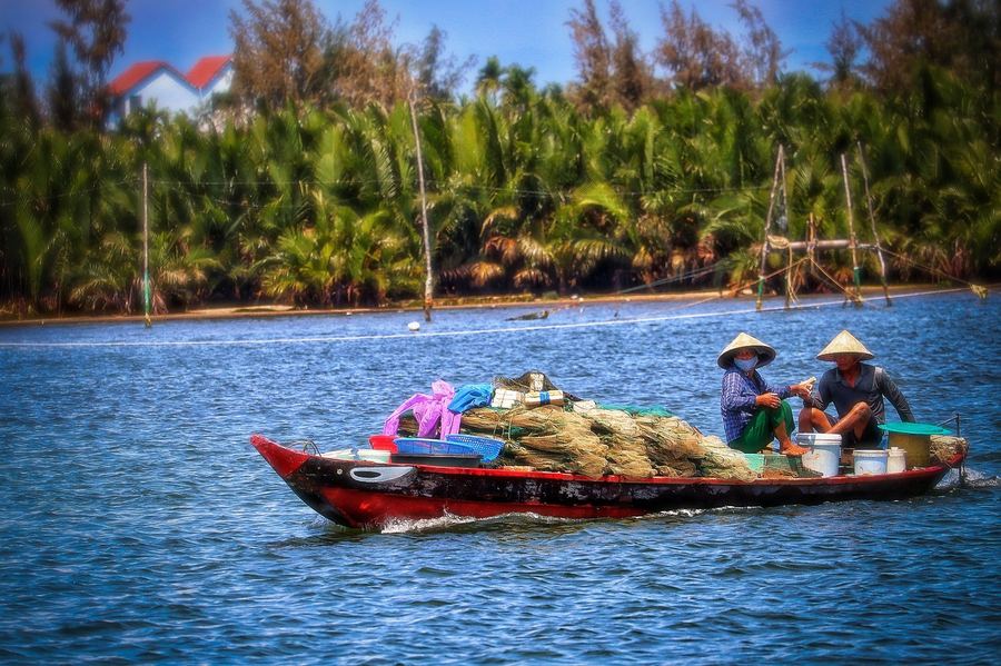 Wooden boat navigating a narrow canal in the Mekong Delta